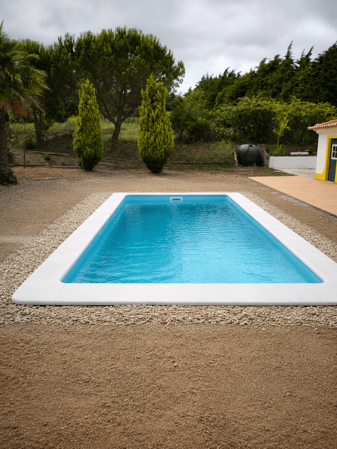 Piscina montada em jardim com gravilha
